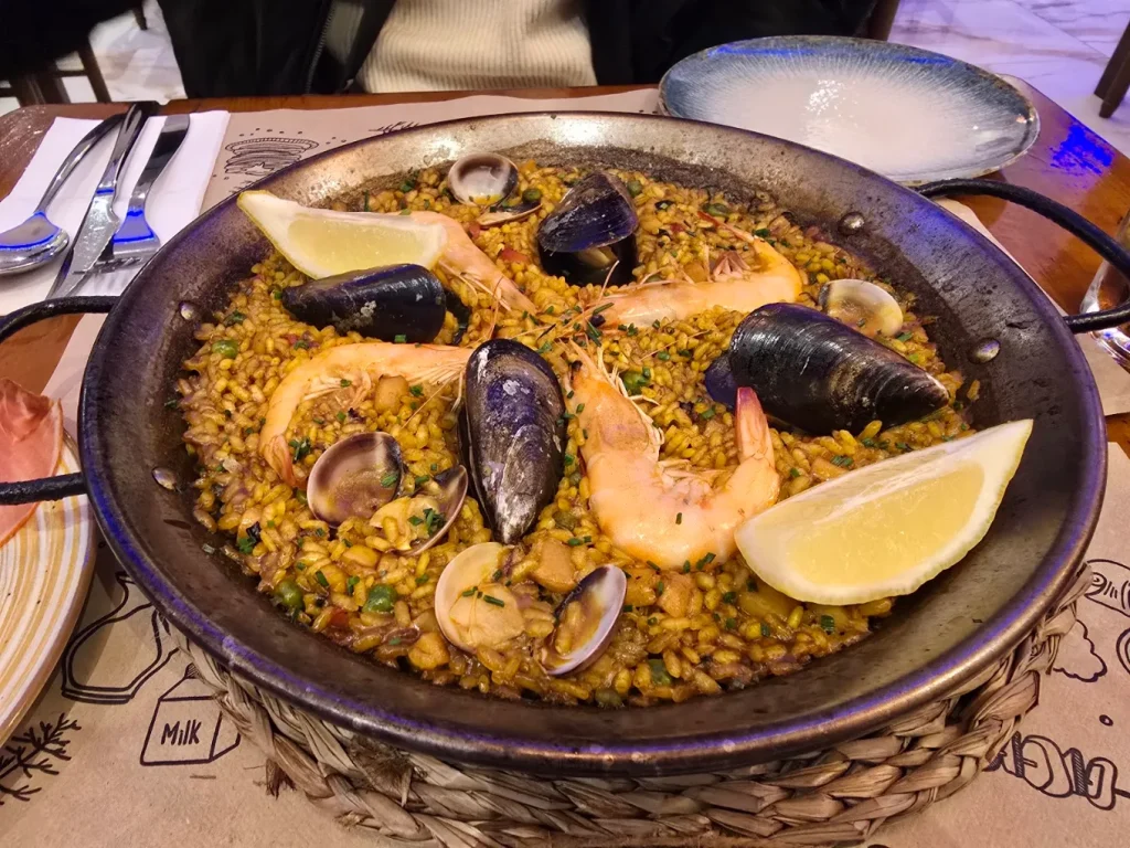 Paella mixta con mejillones, gambas, almejas y limón servida en la mesa