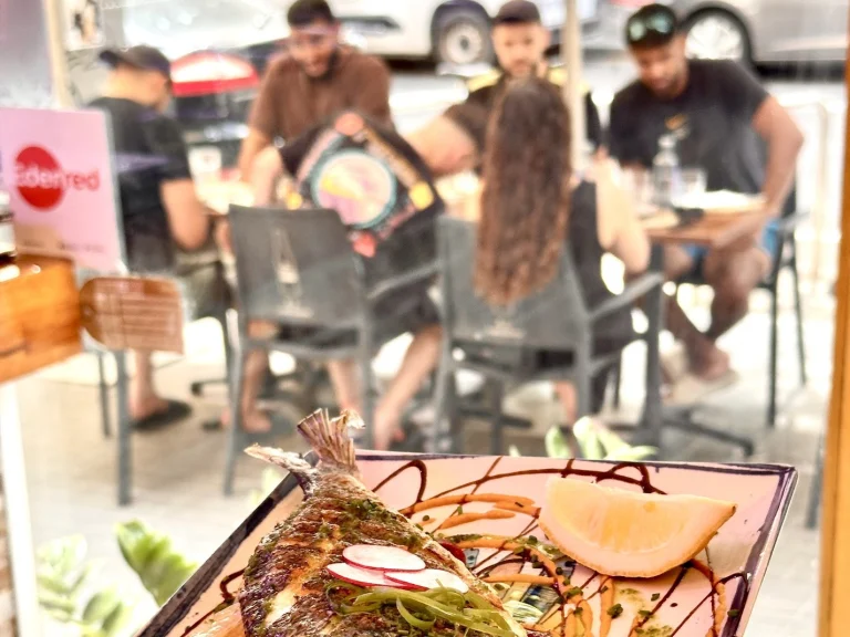 Terraza de Tastari Mediterrani en Carrer de Viladomat, con clientes en las mesas y un plato de dorada en primer plano